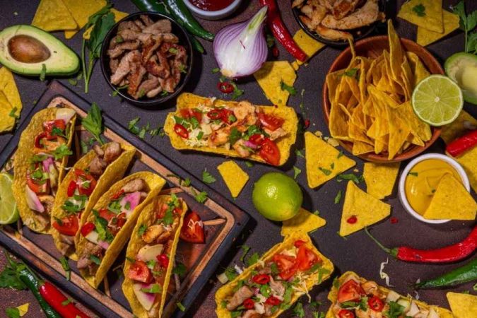 Un étal de cuisine de rue mexicaine avec des tacos garnis, des nachos croustillants et des ingrédients frais colorés.
