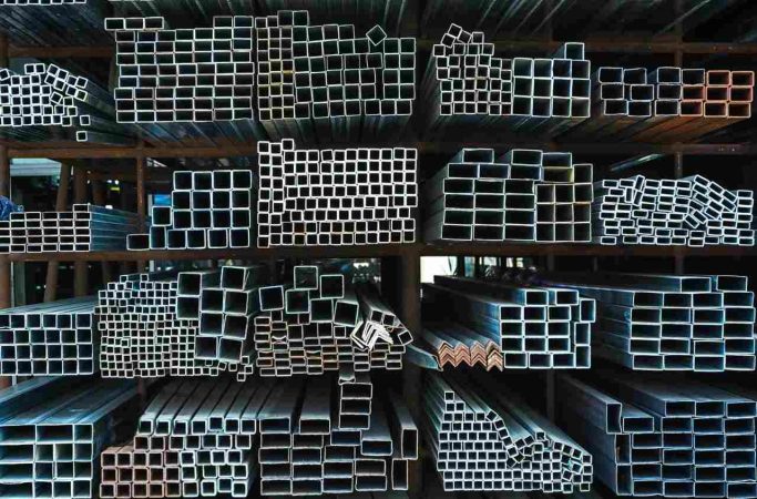 Étagères de rangement d'un entrepôt présentant des faisceaux de tubes et barre de fer de différentes sections.
